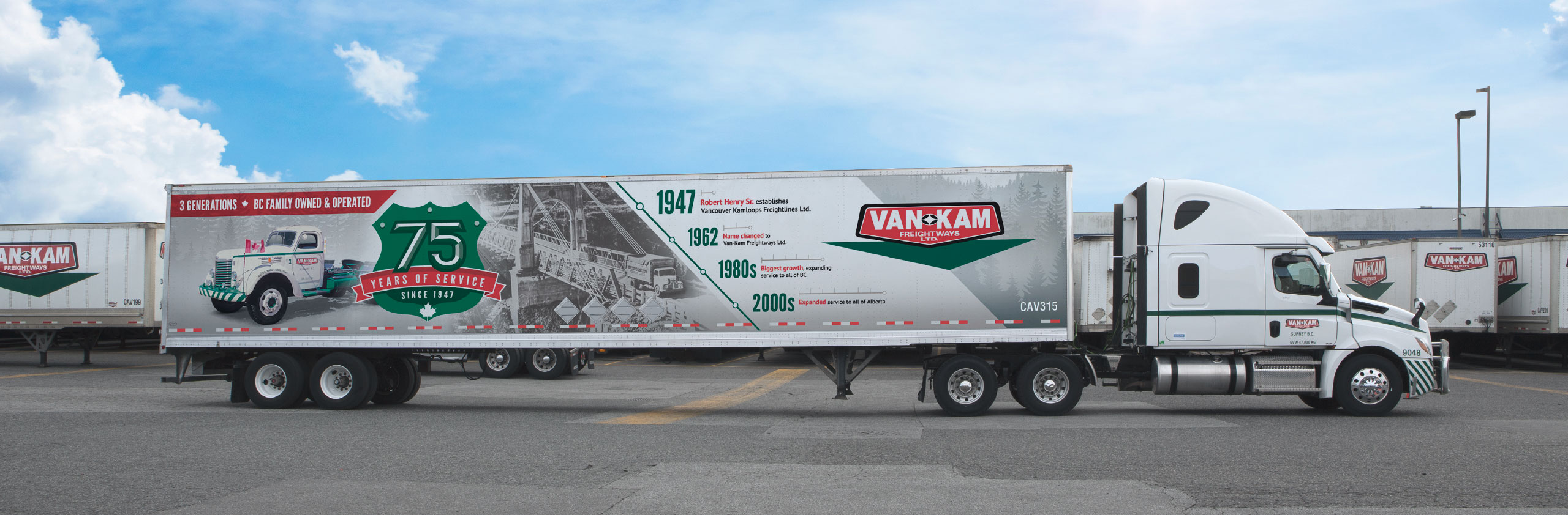 Side view of Van Kam highway truck with 75th anniversary trailer in yard